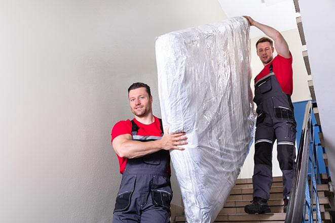 team of workers lifting a box spring out of a house in Langley